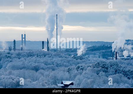 Hängebrücke und Industrie hinter einem eisigen Winterwald Stockfoto