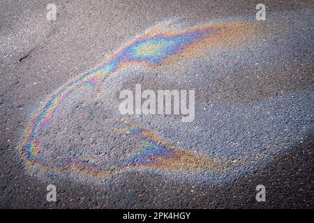 Verschmutzter mehrfarbiger Fleck vom Motoröl auf Asphalt. Konzept der Umweltverschmutzung. Stockfoto