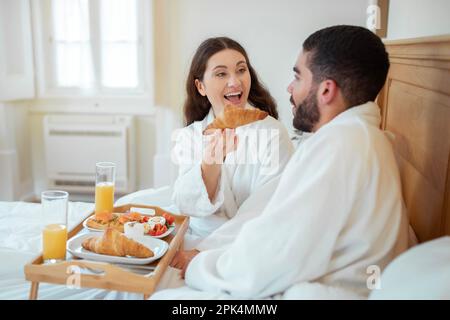 Frau Füttert Ehemann Gibt Croissant Frühstück Im Bett Drinnen Stockfoto