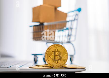 Bitcoin-Münzen neben einem kleinen Spielzeugwagen mit Pappkartons im Hintergrund. Internationales Zahlungskonzept für Netzwerke. Stockfoto