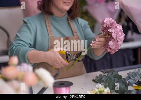 Im Blumenladen, Frau mit professioneller Blumenhandlung, die Blumen aussucht und schöne Blumensträuße kreiert Stockfoto