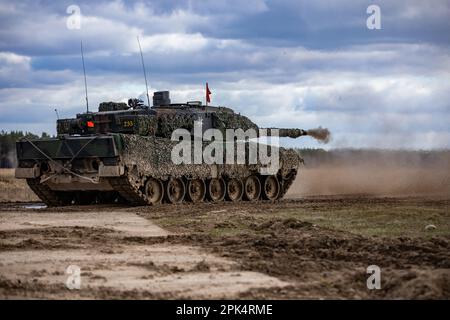 Deutsche Soldaten, die dem 93. Panzerlehr-Demonstrationsbataillon, 9. Panzerlehr-Brigade, 1. Panzerdivision, zugeteilt wurden, fuhren während einer kombinierten Feuerübung in Bemowo Piskie, Polen, am 3. April 2023 einen Leopard 2A6-Panzer auf das Gelände. Die Mission der 4. Infanterieabteilung in Europa besteht darin, sich an multinationalen Schulungen und Übungen auf dem ganzen Kontinent zu beteiligen und mit NATO-Verbündeten und regionalen Sicherheitspartnern zusammenzuarbeiten, um V Corps, Amerikas zukunftsgerichtetes Korps in Europa, mit Kampfkräften zu versorgen. (USA Armeenationalgarde (Foto von Sergeant John Schoebel) Stockfoto