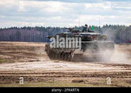 Deutsche Soldaten, die dem 93. Panzerlehr-Demonstrationsbataillon, 9. Panzerlehr-Brigade, 1. Panzerdivision, zugeteilt wurden, fuhren während einer kombinierten Feuerübung in Bemowo Piskie, Polen, am 3. April 2023 einen Leopard 2A6-Panzer auf das Gelände. Die Mission der 4. Infanterieabteilung in Europa besteht darin, sich an multinationalen Schulungen und Übungen auf dem ganzen Kontinent zu beteiligen und mit NATO-Verbündeten und regionalen Sicherheitspartnern zusammenzuarbeiten, um V Corps, Amerikas zukunftsgerichtetes Korps in Europa, mit Kampfkräften zu versorgen. (USA Armeenationalgarde (Foto von Sergeant John Schoebel) Stockfoto