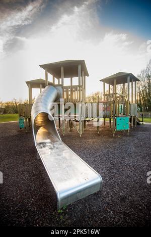 Kinderspielplatz, hölzerne Spielzeugfestung mit großer Metallrutsche und Kletterwand mit Griffen Stockfoto