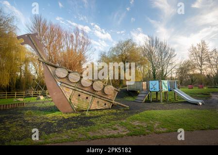 Klettergerüst aus Holz im Freien auf einem öffentlichen Spielplatz mit Rutsche im Hintergrund. Stockfoto