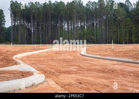 Betonkanten in neuen Wohngebieten wurden auf roten Lehmboden gegossen. Stockfoto