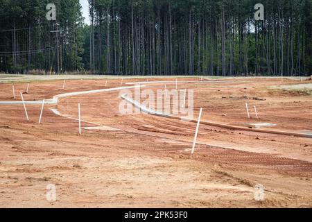 Betonkanten in neuen Wohngebieten wurden auf roten Lehmboden gegossen. Stockfoto