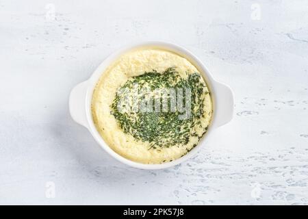 Eine weiße Backform mit einem gekochten Omelett nach dem Dämpfen auf hellblauem Hintergrund. Omelette kochen, hausgemachte gesunde Speisen Stockfoto