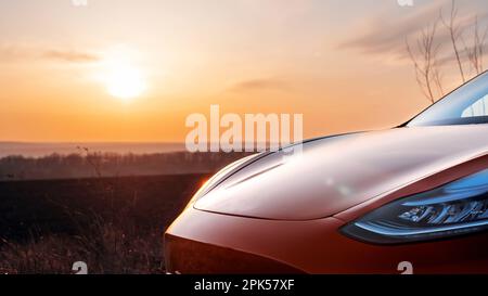 Nahansicht eines geparkten roten Elektroautos mit Blick auf die Sonne im Hintergrund Stockfoto