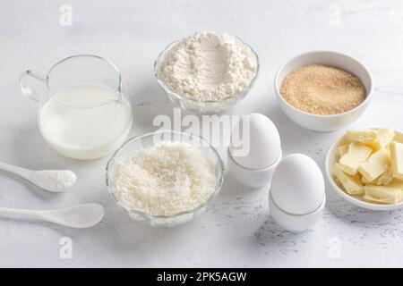 Zutaten für die Zubereitung von Muffins aus weißer Schokolade: Mehl, Milch oder Buttermilch, Eier, Kokosflocken, weiße Schokolade, Brauner Zucker, Salz und bakin Stockfoto