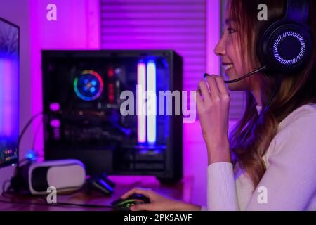 Junge Frau mit Kopfhörern, die Computerspiele spielt Stockfoto