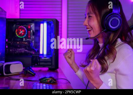 Junge Frau mit Kopfhörern, die Computerspiele spielt Stockfoto