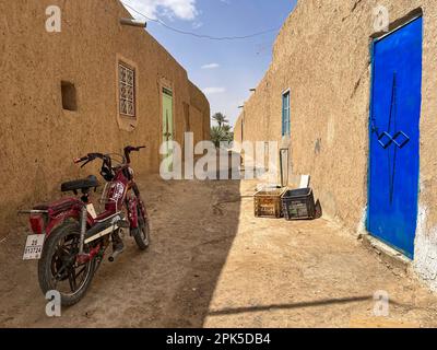 Sahara-Wüste, Marokko, Afrika: Ein Motorrad in einer Gasse in Merzouga, Abfahrtsort für Touristen, die die Sandwüste und die Erg Chebbi-Dünen besuchen Stockfoto