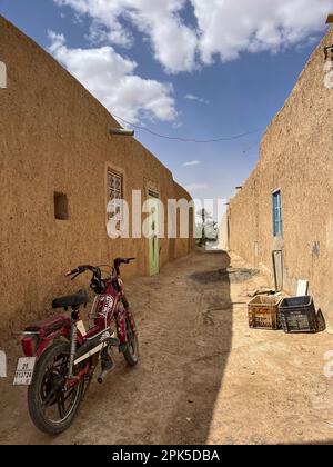 Sahara-Wüste, Marokko, Afrika: Ein Motorrad in einer Gasse in Merzouga, Abfahrtsort für Touristen, die die Sandwüste und die Erg Chebbi-Dünen besuchen Stockfoto