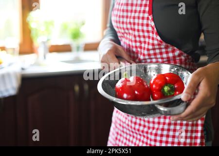 Eine Frau hält ein Sieb mit frischen Paprika in der Küche, Nahaufnahme. Platz für Text Stockfoto