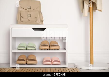 Aufbewahrungsschrank mit verschiedenen Paar Gummipantoffeln in der Nähe der weißen Wand im Raum Stockfoto