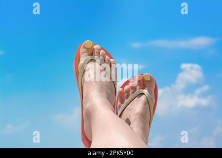 Frau in stylischen pinkfarbenen Flip-Flops am blauen Himmel, Nahaufnahme der Füße Stockfoto