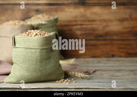 Säcke mit Weizenkörnern, Holzwand, Platz für Text Stockfoto