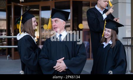 Klassenkameraden in Abschlusskleidern. Barrierefreie Bildung für alle Altersgruppen. Stockfoto