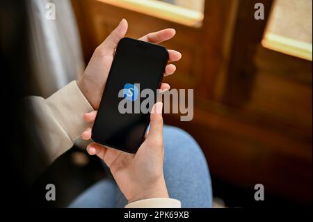 Chiang Mai, Thailand - April 05 2023: Eine Frau, die Skype auf ihrem Smartphone nutzt und Kontakt mit jemandem hat. IPhone mit Skype-Logo auf dem Bildschirm. Stockfoto