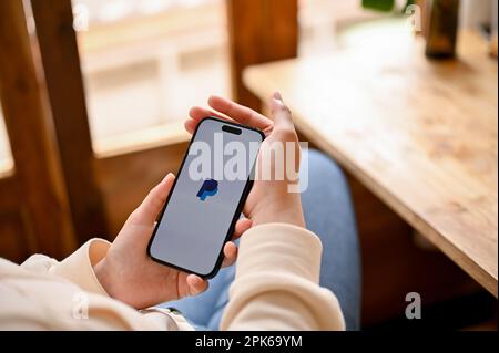 Chiang Mai, Thailand - April 05 2023: Nahaufnahme einer Frau, die PayPal auf ihrem iPhone verwendet. Logo der PayPal App auf dem iPhone-Bildschirm. Stockfoto