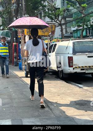 Bangkok, Thailand. 06. April 2023. Eine Frau schützt sich in Bangkok mit einem Sonnenschirm vor der Sonne. Eine ungewöhnlich schwere Hitzewelle hat derzeit große Teile Thailands im Griff. (Dpa '50 Grad in der Sonne: Hitzewelle bringt Thailand in den Griff') Kredit: Carola Frentzen/dpa/Alamy Live News Stockfoto