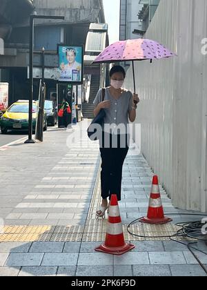 Bangkok, Thailand. 06. April 2023. Eine Frau schützt sich in Bangkok mit einem Sonnenschirm vor der Sonne. Eine ungewöhnlich schwere Hitzewelle hat derzeit große Teile Thailands im Griff. (Dpa '50 Grad in der Sonne: Hitzewelle bringt Thailand in den Griff') Kredit: Carola Frentzen/dpa/Alamy Live News Stockfoto