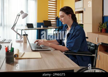 Junge Geschäftsführerin, die in einem modernen Büro mit einem Laptop arbeitet Stockfoto