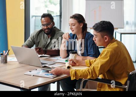 Positives, vielfältiges Business-Team, das Trends bei der Besprechung diskutiert Stockfoto