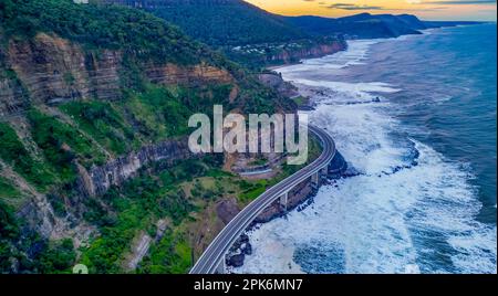 Ein Luftblick auf die Seacliff Bridge entlang der Küste am Pazifischen Ozean in Wollongong, New South Wales, Australien mit Meereswellen. Stockfoto