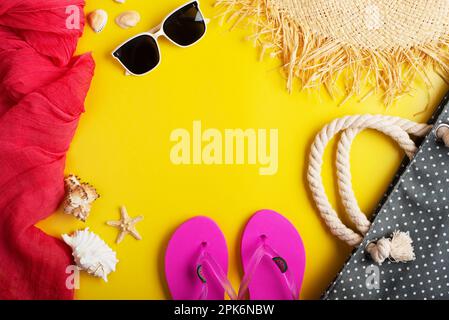 Strohhut Sonnenbrillen Flip-Flops Strandtasche auf gelbem Hintergrund Urlaubsreiseplanung Modell Stockfoto