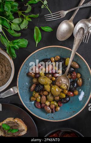 Tisch serviert mit Tapenade, gemischten marinierten Oliven (grün) (schwarz und violett) in Keramikschüssel und Basilikumblättern. Vorspeisen aus der französischen provence und Stockfoto