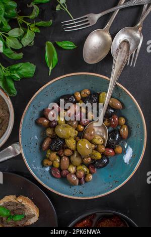 Tisch serviert mit Tapenade, gemischten marinierten Oliven (grün) (schwarz und violett) in Keramikschüssel und Basilikumblättern. Vorspeisen aus der französischen provence und Stockfoto