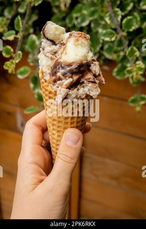 Weibliche Hand mit köstlichem schokoladeneis aus amerikanischer Vanille. Leckeres hausgemachtes Eis in der Waffelform. Glutenfreies veganes Milcheis. Stockfoto