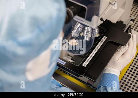 Ulm, Deutschland. 04. April 2023. Mitarbeiter der TRUMPF Photonic Components GmbH sitzen an Arbeitsplätzen in der Reinraumproduktion, an denen Wafer mit VCSEL-Laserdioden überprüft werden. Kredit: Marijan Murat/dpa/Alamy Live News Stockfoto