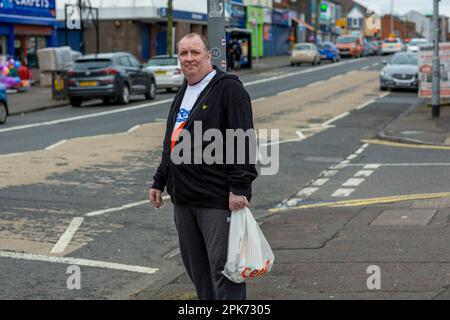 Ein Mann, der auf der Shankill Road in Belfast, County Antrim, Nordirland, Großbritannien, einkaufen geht Stockfoto