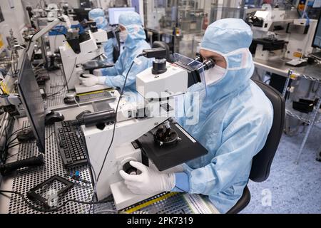 Ulm, Deutschland. 04. April 2023. Mitarbeiter der TRUMPF Photonic Components GmbH sitzen an Arbeitsplätzen in der Reinraumproduktion, an denen Wafer mit VCSEL-Laserdioden überprüft werden. Kredit: Marijan Murat/dpa/Alamy Live News Stockfoto