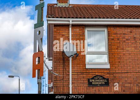 Buchstaben Rechtschreibung I.R.A. ist hoch auf einem Lampenpfahl in West Belfast , Nordirland , zu sehen . Stockfoto