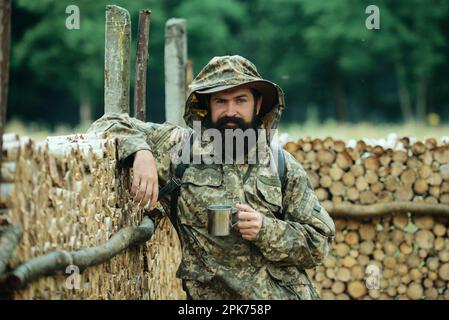 Porträt des Reisenden Mann trinken Tee oder heißen Kaffee mit Emaille-Tasse, Metall-Becher. Reise Lifestyle Landschaft und Abenteuer Konzept. Mensch in der Natur. Stockfoto