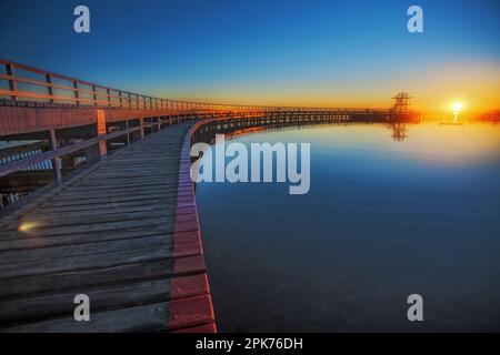 Eine hölzerne Promenade umschließt die ruhige Eastern Beach Swimming Enclosure bei Sonnenaufgang mit einer Tauchplattform in der Ferne Geelong, Victoria, Australien Stockfoto