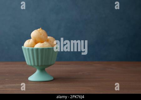 Creme-Puffs im Becher isoliert auf Holztisch Stockfoto