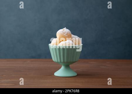 Creme-Puffs im Becher isoliert auf Holztisch Stockfoto