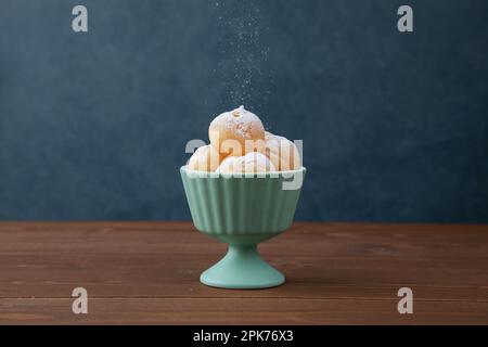 Creme-Puffs im Becher isoliert auf Holztisch Stockfoto