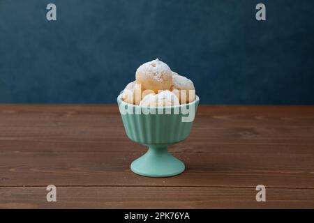 Creme-Puffs im Becher isoliert auf Holztisch Stockfoto