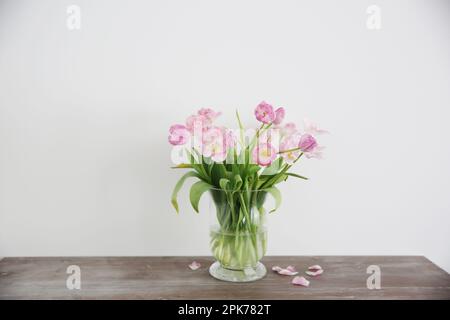 Strauß rosa Tulpenblüten in Vase auf Holztisch. Stockfoto