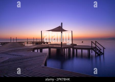 Holzsteg am Strand von Carmol im Mar Menor, bei einem warmen Sonnenaufgang, in Cartagena, Region Murcia, Spanien Stockfoto