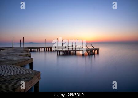 Holzsteg am Strand von Carmol im Mar Menor, bei einem warmen Sonnenaufgang, in Cartagena, Region Murcia, Spanien Stockfoto