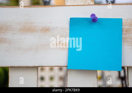 Violette Kartennadel blaue quadratische Papiernotiz auf weiß lackiertem Holzgitter mit leerem freien Platz für Vorlage oder leerem Kopierbereich Stockfoto