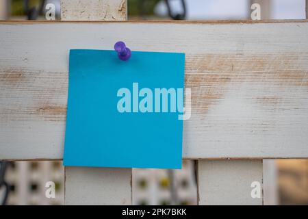 Violette Kartennadel blaue quadratische Papiernotiz auf weiß lackiertem Holzgitter mit leerem freien Platz für Vorlage oder leerem Kopierbereich Stockfoto