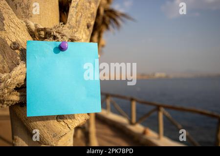 Seil mit Holzpfosten und einem blauen quadratischen Papierzettel mit freiem Platz für Vorlage oder leeren Kopierbereich Stockfoto